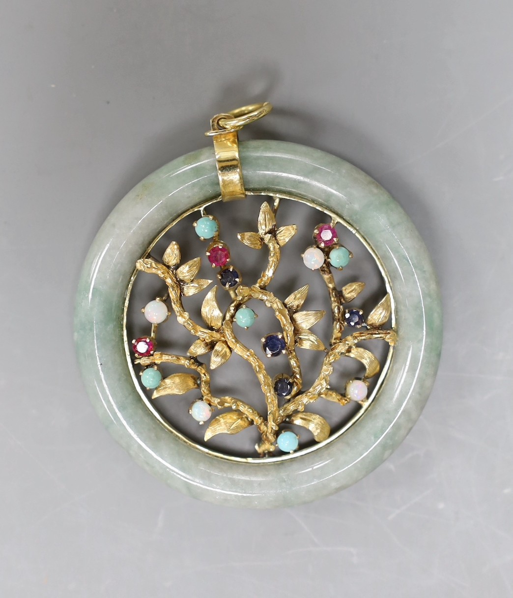 A 14k yellow metal and multi gem set circular jade pendant, diameter 51mm, gross weight 28.8 grams.